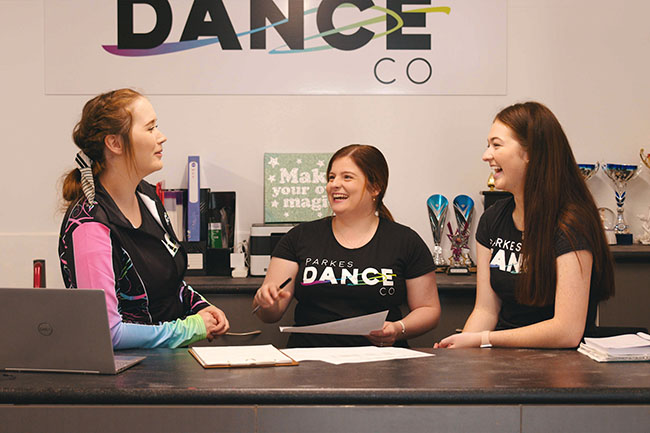Three women standing behind a counter laughing