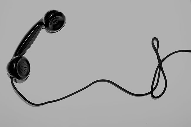 Black and white image of a phone and cord on a white background